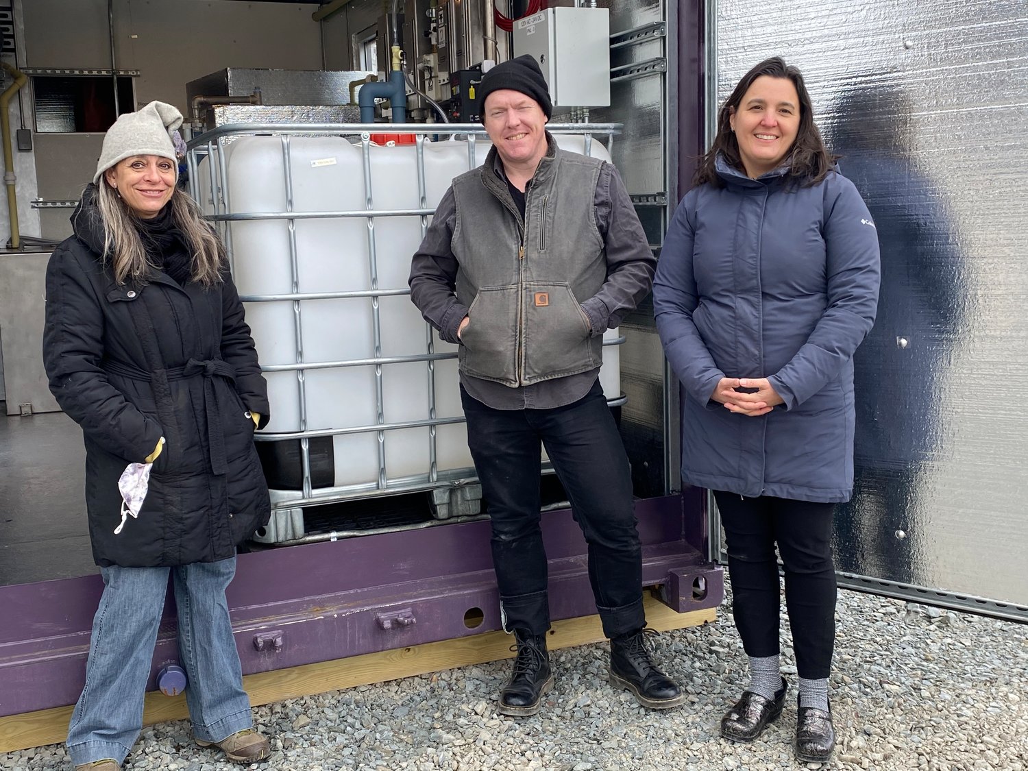 Tusten Energy Committee (TEC) Chair Brandi Merolla, left, member Scott Porter, and Jennifer Porter stand in front of the container which will eventually be filled with probiotic plant food. Jennifer, a consultant for solid waste management, learned of the digester at a trade show in 2018. When the NY Department of Conservation called for foodwaste projects in 2018, Jennifer worked with the TEC, to apply and receive full funding for the project. Good Find Farm, who assisted with the grant application is interested in using the plant food on their farm in Damascus, PA.